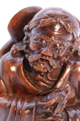 A mid 19th century Japanese Okimono of a seated man holding a bat