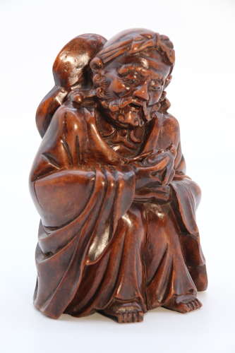 A mid 19th century Japanese Okimono of a seated man holding a bat