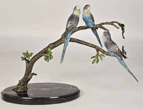 A large Austrian cold painted bronze study of three budgerigars perched on a leafy branch.