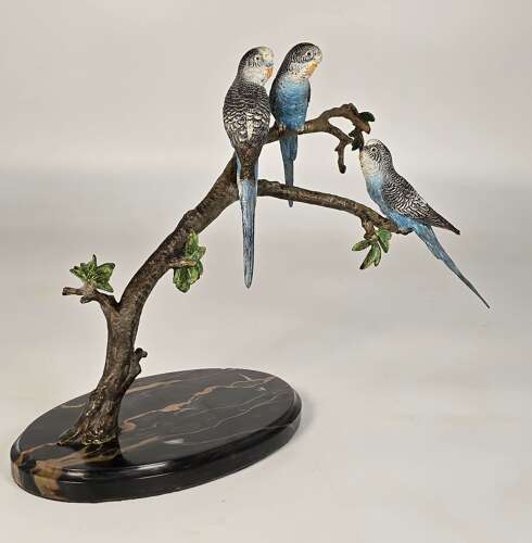 A large Austrian cold painted bronze study of three budgerigars perched on a leafy branch.